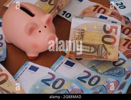 Banca di porcellini circondata da banconote europee da 50, 20 e 10 euro Foto Stock