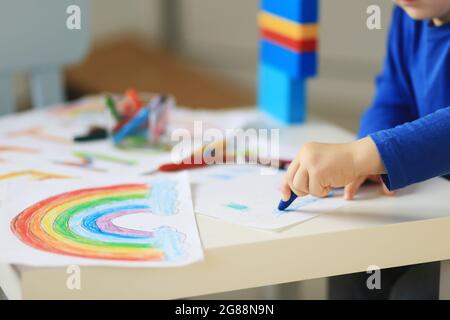 Un ragazzo di 4-7 anni si siede al tavolo e disegna con vernici multicolore. Creatività dei bambini. Hobby per bambini. Foto di alta qualità Foto Stock