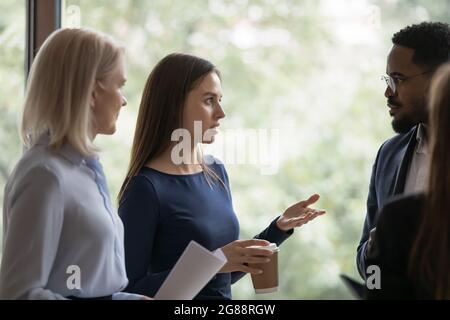 Un giovane dipendente serio che parla con colleghi diversi Foto Stock