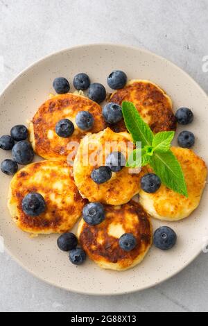 Torta al formaggio Cottage con mirtilli e menta in un piatto su sfondo grigio Foto Stock
