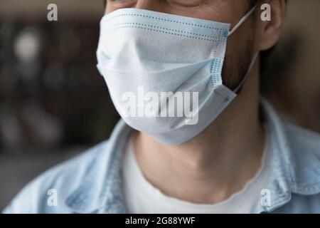 Primo piano giovane uomo che indossa maschera medica monouso. Foto Stock