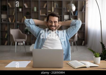 Felice giovane uomo in occhiali che si rilassa durante la giornata di lavoro. Foto Stock