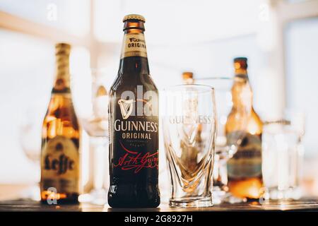 Lviv, Ucraina - 1 dicembre 2017: Bottiglia e bicchiere di birra Guinness in luce calda e soleggiata sullo sfondo di birre Leffe e Hoegaarden sul banco. Hoegaa Foto Stock