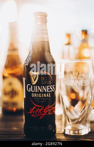 Lviv, Ucraina - 1 dicembre 2017: Bottiglia e bicchiere di birra Guinness in luce calda e soleggiata sullo sfondo di birre Leffe e Hoegaarden sul banco. Hoegaa Foto Stock