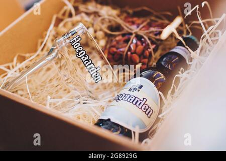 Lviv, Ucraina - 1 dicembre 2017: Bottiglia di birra Hoegaarden, bicchiere e spuntini di noci salate sulla paglia in una confezione regalo. Elegante confezione regalo per compleanno uomo, fa Foto Stock