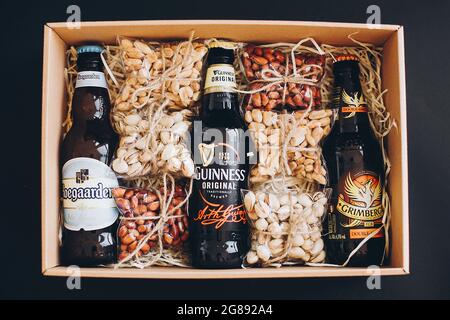 Lviv, Ucraina - 1 dicembre 2017: Bottiglie di birra Hoegaarden, Grimbergen e Guinness con etichetta e spuntini di noci salate sulla paglia in scatola regalo. GIF elegante Foto Stock
