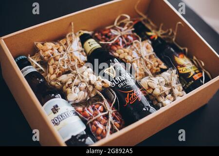 Lviv, Ucraina - 1 dicembre 2017: Bottiglie di birra Hoegaarden, Grimbergen e Guinness con etichetta e spuntini di noci salate sulla paglia in scatola regalo. GIF elegante Foto Stock