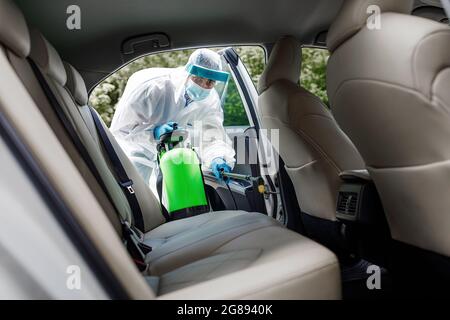 Detergente speciale che indossa la suite di Hazmat, dispositivi di protezione individuale DPI con spray chimico all'alcool Foto Stock