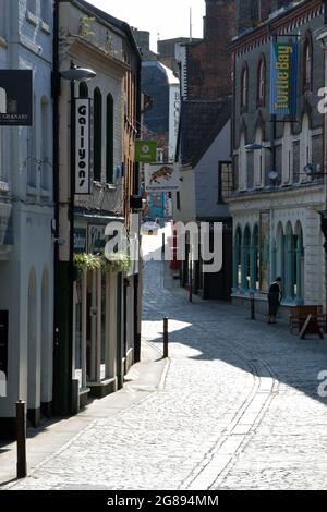 Una donna sweep il marciapiede di fronte al suo negozio in ciottolato Bedford Street, Norwich, Regno Unito Foto Stock