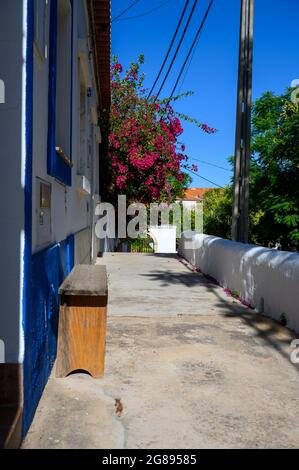 C'è una piccola panchina di fronte ad una tipica casa portoghese decorata con molti fiori. Foto Stock