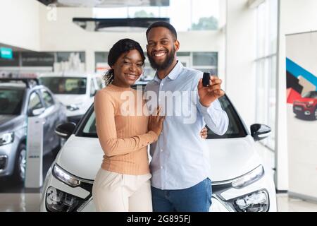 Felici proprietari. Allegro sposi neri che tiene la chiave della loro nuova automobile Foto Stock