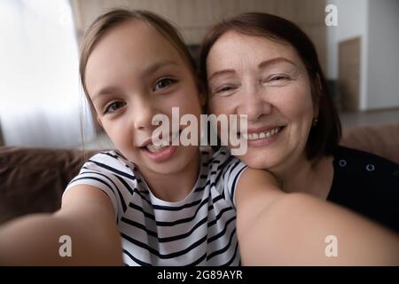 Ragazza felice e nonna positiva prendendo selfie insieme Foto Stock