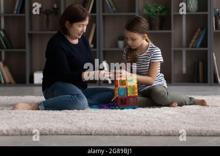 Grandkid e nonna che giocano a casa, impegnati nel gioco di costruzione Foto Stock