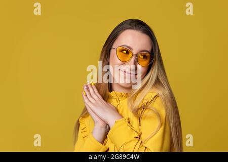 donna timida in occhiali da sole su sfondo giallo. Foto Stock