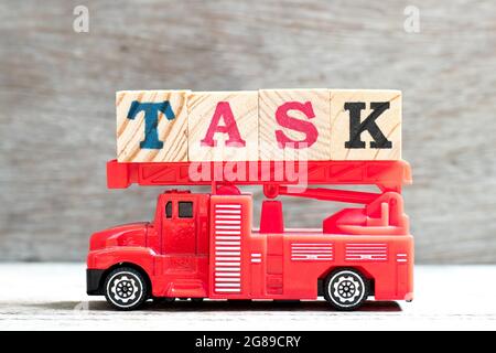Carrello giocattolo a scala antincendio tenere il blocco di lettere in attività di parola su sfondo di legno Foto Stock