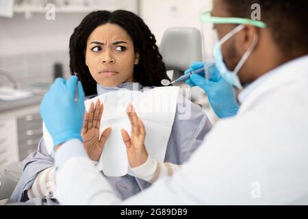 Ritratto di una paziente femmina nera spaventata durante il check-up con dentista Foto Stock