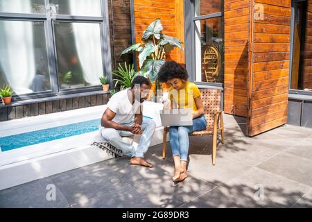 Afro coppia americana in casa in giardino - bella coppia nera passare il tempo insieme a guardare un video online su computer portatile Foto Stock