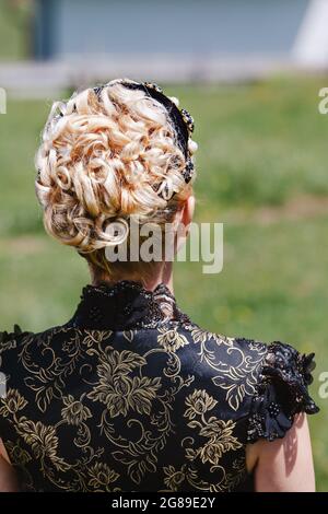 Ritratto di Donna bionda in pizzo Abito con archetto e capelli ricci, da dietro Foto Stock