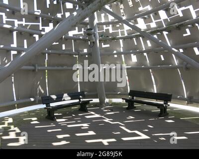 La luce del sole si riflette attraverso i pannelli in acciaio inossidabile sulle due panchine per sedersi all'interno di una delle sculture equine, il Kelpies Tour. Foto Stock