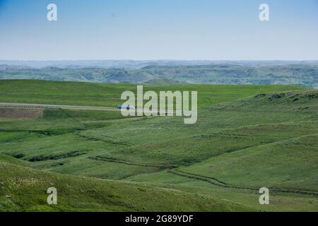 I veicoli viaggiano verso sud sull'Interstate 90 vicino a Story, Wyoming. Trail su collina in primo piano è il percorso del vecchio Bozeman Trail, un ramo dell'Oregon Trail. Foto Stock