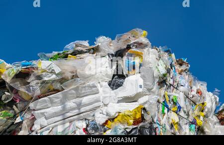 Dettaglio degli involucri di plastica monouso vuoti compressi nella balla su fondo blu. Separazione dei rifiuti da riciclare. Imballaggi usati come sacco, sacco, scatola. Foto Stock