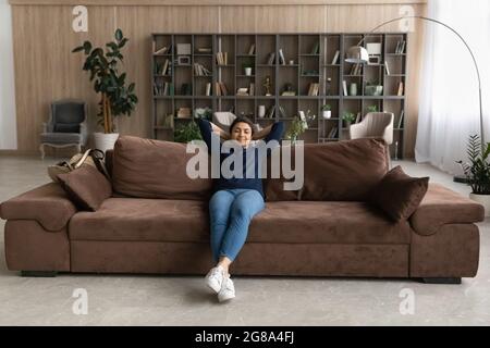 Calma donna indiana rilassarsi sul divano respirare aria fresca Foto Stock