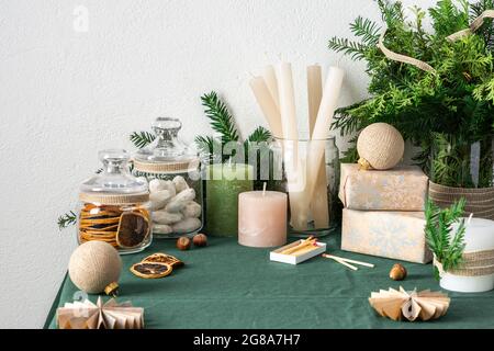 Tavolo festoso decorato Natale o Capodanno, rami thuja e abete rosso, candele e palle di Natale, biscotti in un vaso, scatole regalo e decorazioni Foto Stock