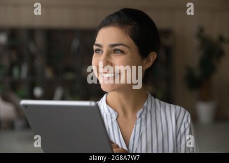 Sorridente donna indiana uso tablet fare piani Foto Stock