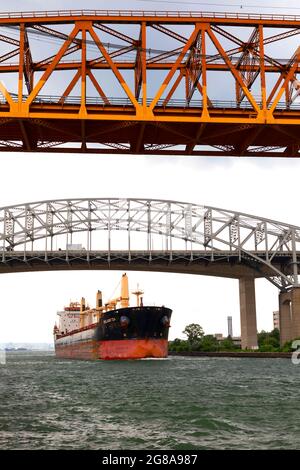 Nave da trasporto che passa sotto il Burlington Canal Lift Bridge e il Burlington Bay James N. Allan Skyway. Burlington, Ontario, Canada. Foto Stock