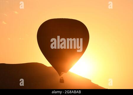 Cappadocia, Turchia. 18 luglio 2021. Il 18 luglio 2021, una mongolfiera si staglia contro il sole sulla Cappadocia, in Turchia. Credit: Mustafa Kaya/Xinhua/Alamy Live News Foto Stock