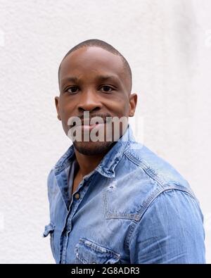 Giovane uomo in camicia casual in denim blu con fondo piano. Foto Stock