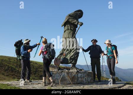 Camino de Santiago (Via di San Giacomo). Pellegrini raffigurati accanto alla statua di bronzo di un pellegrino sull'Alto de San Roque in Galizia, Spagna. La strada francese del Camino de Santiago attraversa questo passo poco prima di raggiungere il villaggio di Hospital da Condesa. La statua disegnata dallo scultore galiziano José María Acuña López fu svelata sul passo nel 1993. Foto Stock