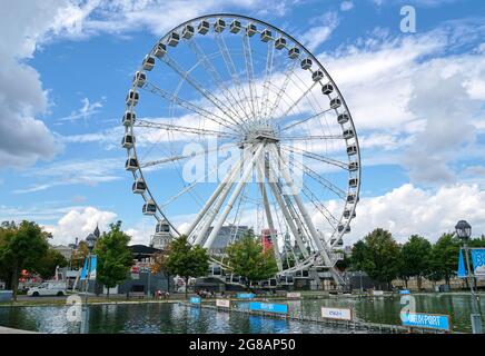 Canada, Montreal - 11 luglio 2021: Vista panoramica della ruota panoramica la Grande Roue de Montreal nel Porto Vecchio di Montreal su cieli blu e nuvole. Il vecchio P. Foto Stock