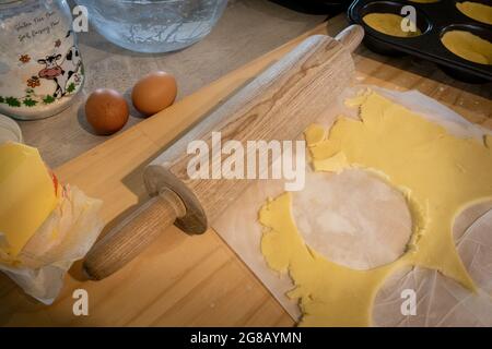 Pasta senza glutine arrotolata su una tavola e usata per rivestire le teglie dei muffin per le conserve Foto Stock