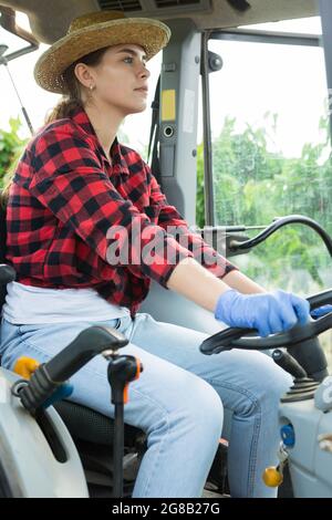 Giovane agricoltore specializzato che lavora su un trattore piccolo in frutteto Foto Stock