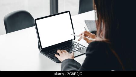 Un'immagine ritagliata di una donna d'affari che si trova in una moderna stanza d'ufficio e utilizza un tablet digitale a schermo vuoto Foto Stock