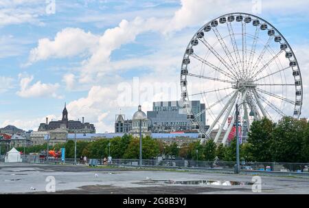Canada, Montreal - 11 luglio 2021: Vista panoramica della ruota panoramica la Grande Roue de Montreal nel Porto Vecchio di Montreal su cieli blu e nuvole. Il vecchio P. Foto Stock