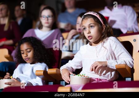 Presteen ragazza con afroamericano amico guardare film al cinema Foto Stock