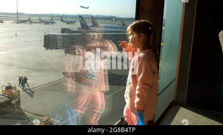 Bambina che guarda l'aereo parcheggiato all'aeroporto di Mosca attraverso la finestra del cancello. Manutenzione e preparazione dell'aeromobile per il reggimento Foto Stock