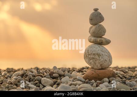 Pietre equilibrate sulla spiaggia all'alba Foto Stock