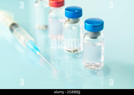 Gruppo di flaconcini con farmaco e siringa sul tavolo su sfondo blu. Spazio di copia. Foto Stock