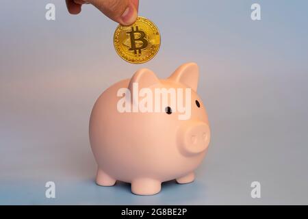 concetto di investimento di criptovaluta. mano maschio che mette il bitcoin nella banca del piggy. Foto Stock