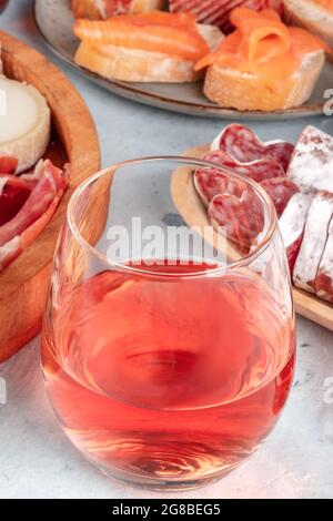 Vino rosato con prosciutto, formaggio e panini al salmone. Tapas spagnole in un bar. Condivisione di cibo. Spuntini mediterranei Foto Stock