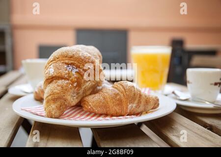 Primo piano della colazione italiana con cornetto brioches con marmellata, cappuccino, caffè, succo d'arancia su un tavolo di legno nel bar italiano Foto Stock
