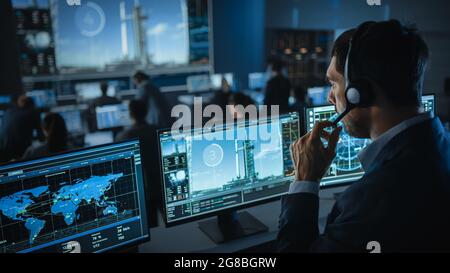 Il Direttore di volo conta i secondi prima del lancio di Space Rocket. Team in Mission Control testimone di successo Lift Off. I dipendenti del controllo di volo siedono Foto Stock