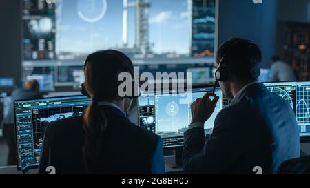 Il Direttore di volo conta i secondi prima del lancio di Space Rocket. Team in Mission Control testimone di successo Lift Off. I dipendenti del controllo di volo siedono Foto Stock