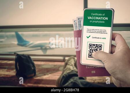 smartphone con codice qr nell'app per confermare la vaccinazione o un test negativo per covid-19. un uomo ha un passaporto e uno smartphone presso l'aeroporto agai Foto Stock