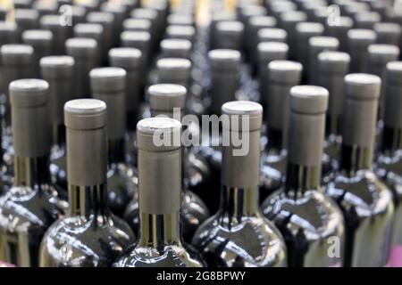 Le bottiglie di vino in una riga, il fuoco selettivo. Negozio di liquori, vino rosso concetto di produzione Foto Stock