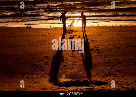 Un cane saluta i suoi proprietari dopo aver fatto una nuotata nel Mare d'Irlanda a Helen's Bay, Co. Down, durante l'alba del Summer Solstice. Foto Stock