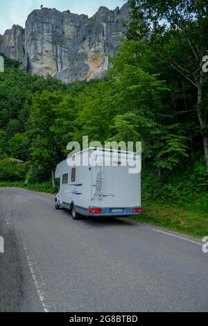 Auto bianca di camper che guida in montagna. Stile di vita avventuroso. Vita dei camper. Viaggiare in montagna Foto Stock